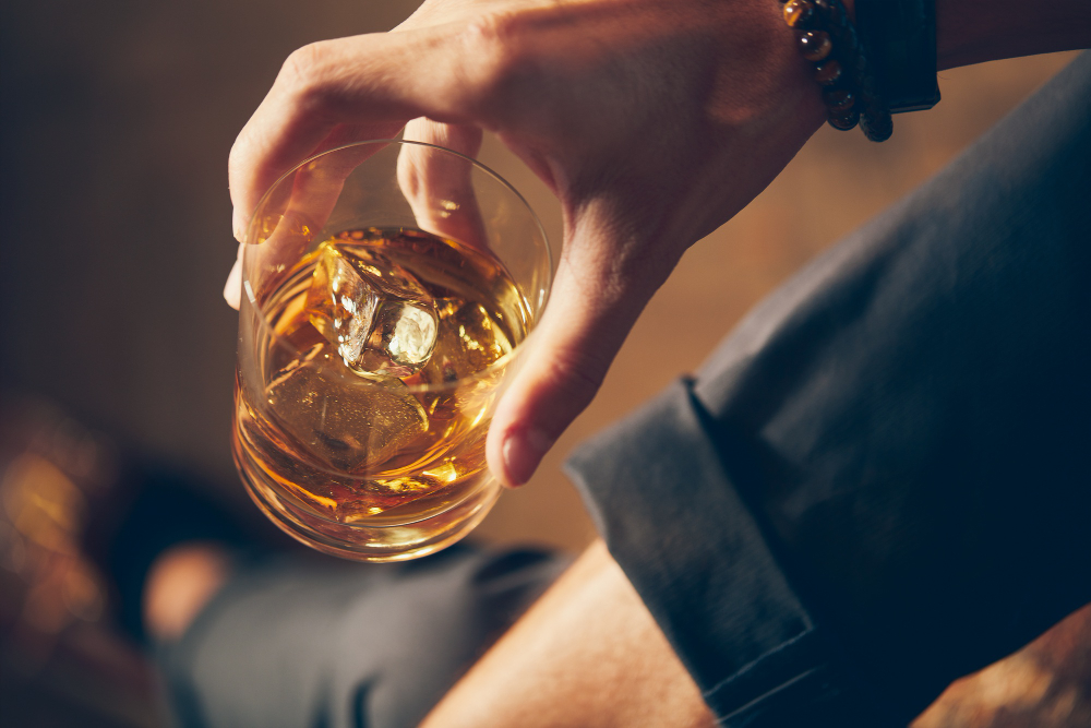 high angle closeup shot of a male holding a glass of whiskey